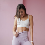 Una chica luciendo abdomen tras una clase de hiporesivos con un pantalon morado y un top blanco.