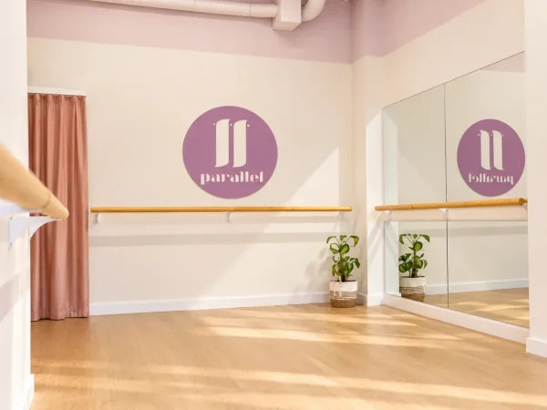 el aula de una clase de barre con el logo de parallel en la pared.